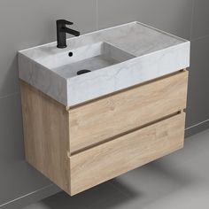 a white sink sitting next to a wooden cabinet with a black faucet on it