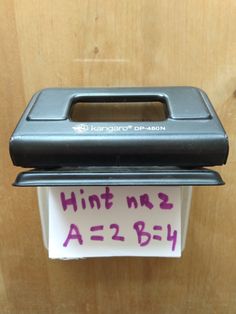 a close up of a paper dispenser on a wooden surface with writing