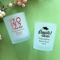 two frosted cups with graduation designs are sitting next to each other on a table