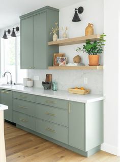 a kitchen with green cabinets and white counter tops