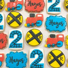 decorated cookies with train tracks and numbers are displayed on a white tablecloth covered surface