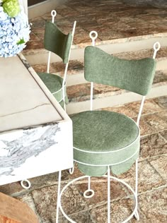 two green chairs sitting next to each other on top of a stone floor near stairs