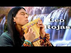 a woman holding an instrument in front of a waterfall with the words leo rojas on it