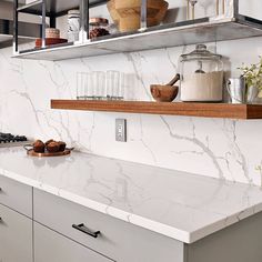 a kitchen with white marble counter tops and stainless steel shelving above the stove top