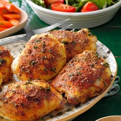 several pieces of chicken on a plate with salad in the background