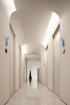 a person walking down a long hallway with white walls