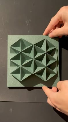 two hands are holding an origami piece