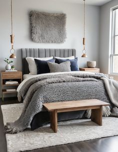 a bedroom with a gray bed and white rugs on the floor, two wooden benches in front of it