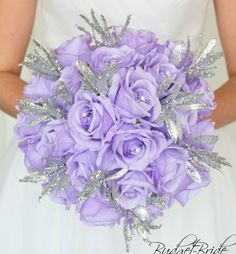 a bride holding a bouquet of purple roses and silver glittered leaves on her wedding day