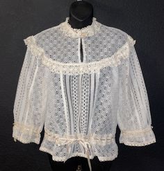 "There are no tags to indicate the maker of this blouse, I'm guessing it is 1970's but it could clearly be much older. I was actually told it was 1930-40's, but I can't be 100% sure. The condition is wonderful, only some discoloration on the inner side of the back of the collar. There is a keyhole neckline, lace ruffle around the high neck as well as a snap closure. There are beige satin ribbons threaded through the waist for cinching and the arm openings, also little satin bows at the neck and Vintage Fashion Lace Trim Tops For Spring, Vintage Lace Top Blouse, Vintage Lace Trim Tops For Spring, Spring Vintage Fashion Tops With Lace Trim, Vintage Daywear Tops, Vintage White Blouse For Spring, Spring Victorian Blouse For Daywear, Vintage Beige Blouse For Spring, Retro White Top For Daywear