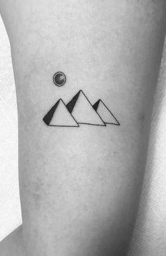 a small black and white mountain tattoo on the right thigh, with a sun above it