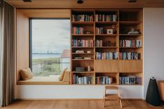 a window seat in front of a bookshelf filled with lots of books next to a large window