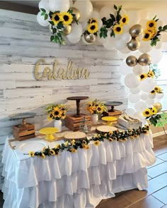 a table with sunflowers and balloons on it