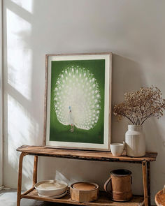 a green and white painting sitting on top of a wooden shelf next to a potted plant