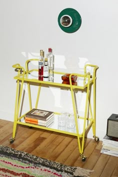 a yellow cart sitting on top of a hard wood floor next to a white wall