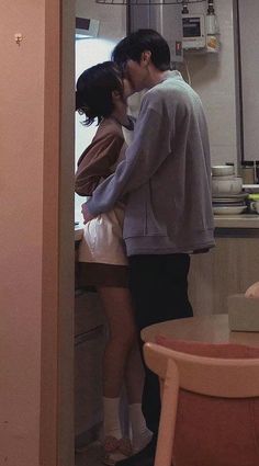 two people standing in a kitchen kissing each other