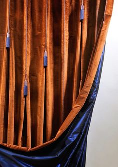 an orange curtain with blue tassels hanging from it's sides and on the side