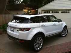 a white range rover parked in front of a house