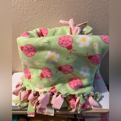 a green blanket with pink flowers and strawberries on it sitting on top of a table