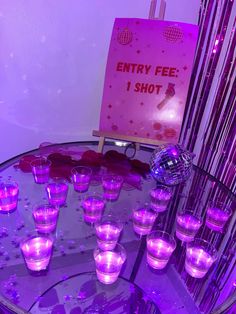 purple lit up shot glasses sitting on top of a glass table with an entry fee sign in the background