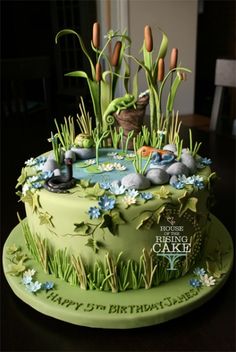 a green cake with flowers and plants on it's top is sitting on a table