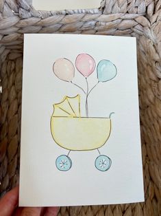 a drawing of a baby carriage with balloons on it's back, in front of a wicker basket