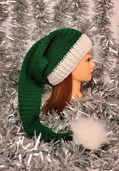 a doll wearing a green and white knitted hat on top of silver tinsel