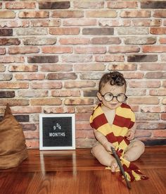 a small child wearing glasses sitting on the floor next to a sign that says, harry potter