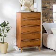 a bedroom scene with focus on the chest of drawers and a bed in the background