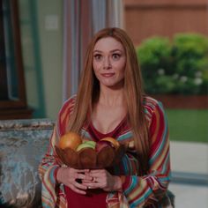 a woman with long hair holding a basket of fruit