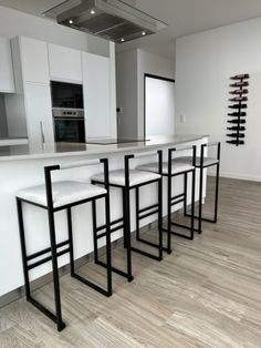 a kitchen with white counter tops and black barstools in front of an oven