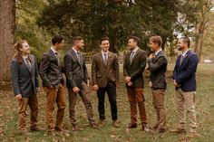 a group of men standing next to each other on top of a grass covered field