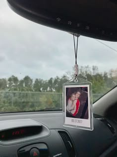 a car dashboard with a photo hanging from the dash board and an air freshener attached to it