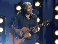 a man playing an acoustic guitar on stage