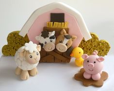 three farm animals are standing in front of a small toy barn with sheep and ducks