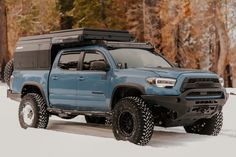 a blue truck is parked in the snow with its roof mounted on it's back