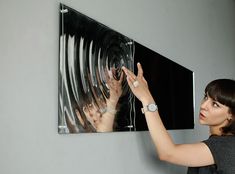 a woman holding her hand up in front of a painting on the wall with two hands