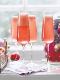 three glasses filled with pink liquid sitting on top of a window sill next to candy