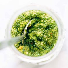 a jar filled with green sauce on top of a white table