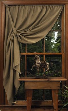 an image of a window with curtains and horses on the windowsill in front of it