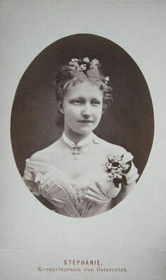 an old black and white photo of a woman with flowers in her hair wearing a dress