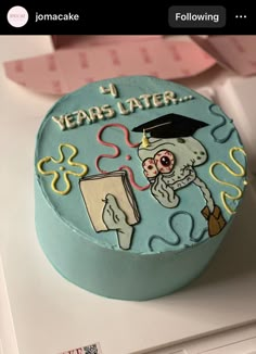 a blue cake decorated with an image of a graduate's cap and book on it