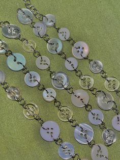 several buttons are attached to a chain on a green surface with other items in the background