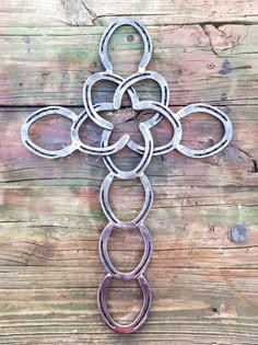 a cross made out of metal rings on a wooden surface