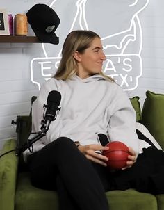 a woman sitting on top of a green couch holding a red ball