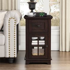 an end table with a drawer on it in front of a white couch and window