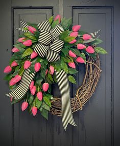 a wreath with pink tulips and green leaves hangs on the front door,