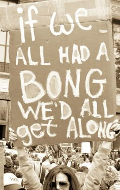 a woman holding up a sign that says if we all had a bong we'd all get along