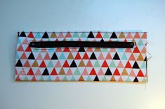 a zippered pouch with triangles on the front and inside, sitting on a white surface