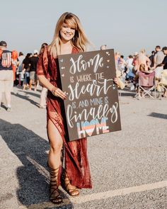 a woman holding a sign that says some is where the heart is and mine is home